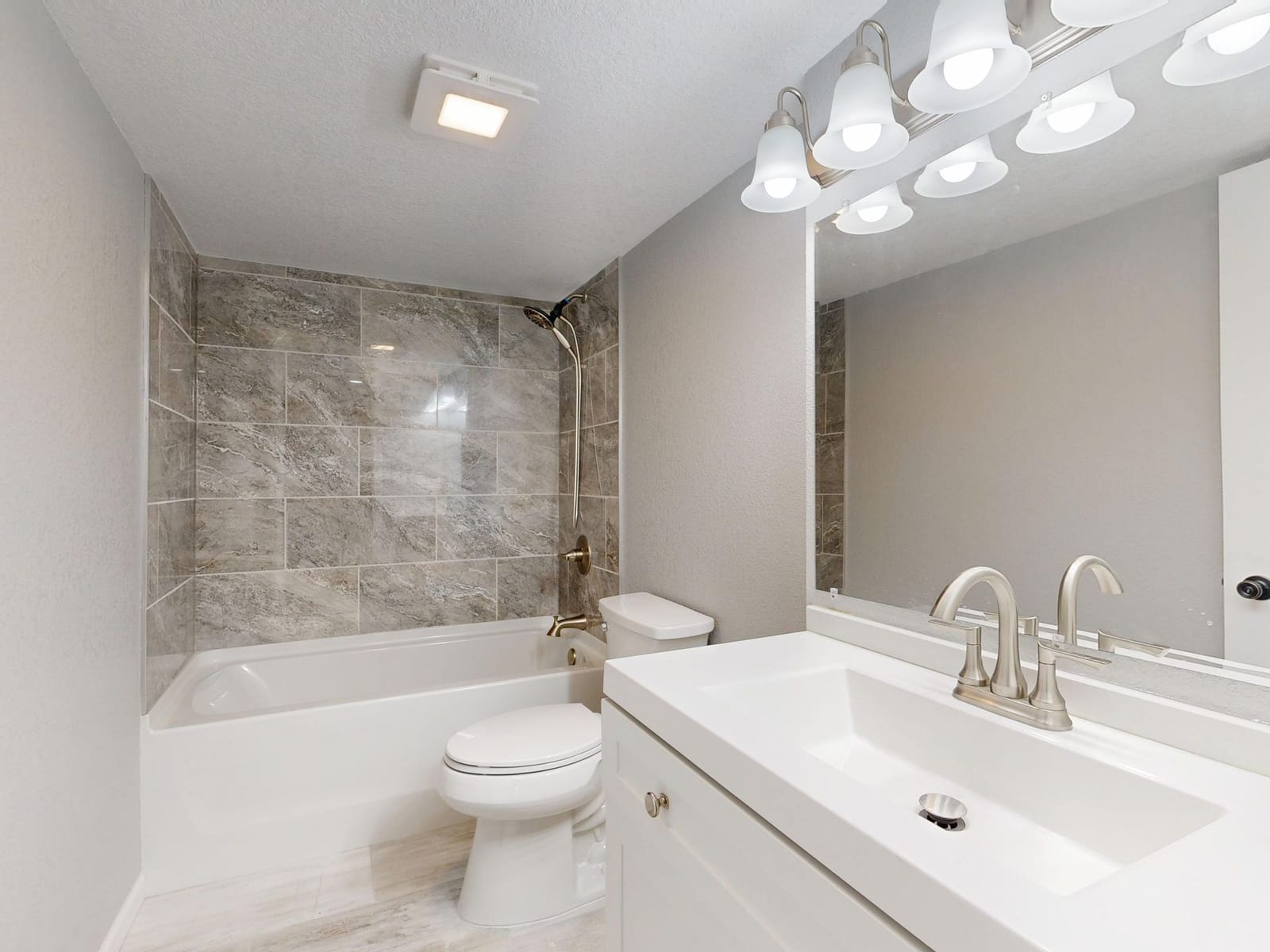 Von Grund auf saniertes Altbau-Bad mit neu verfliester Wanne in Marmoroptik und heller Waschtischzeile